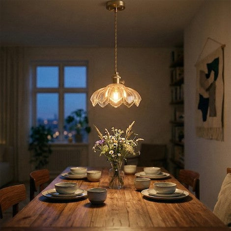 A retro glass flower pendant light casting a warm glow over a wooden dining table.