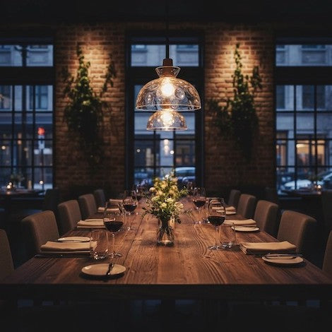 A beautifully set farmhouse dining table under warm hammered glass pendant lights, creating a ceremonial atmosphere.