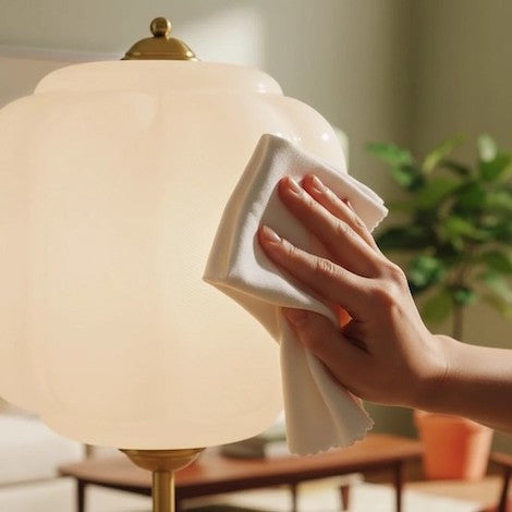 Cleaning a textured opal glass floor lamp with a microfiber cloth.