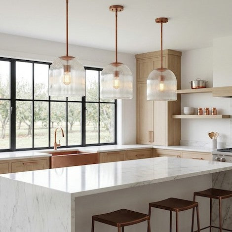 Three ribbed glass pendants with copper accents arranged symmetrically over a modern farmhouse kitchen island.
