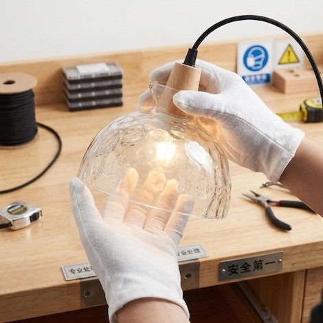 Professional demonstration of handling a hammered glass pendant light with protective gloves for safety and cleanliness.