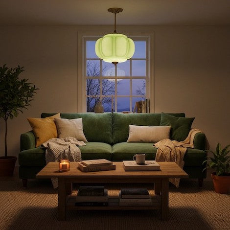 Cozy living room atmosphere featuring a glowing green glass pumpkin pendant light.