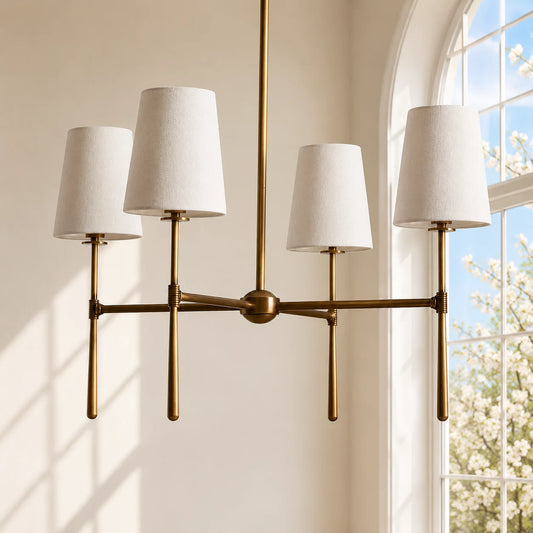 Antique brass four-light chandelier against a sunlit cream wall