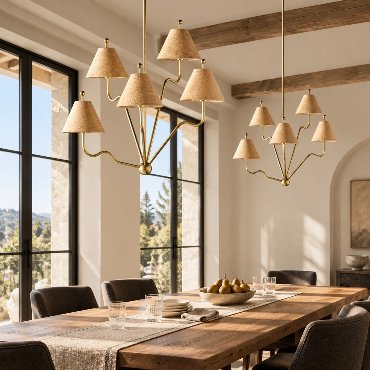 Two Isolde brass chandeliers above a long dining table