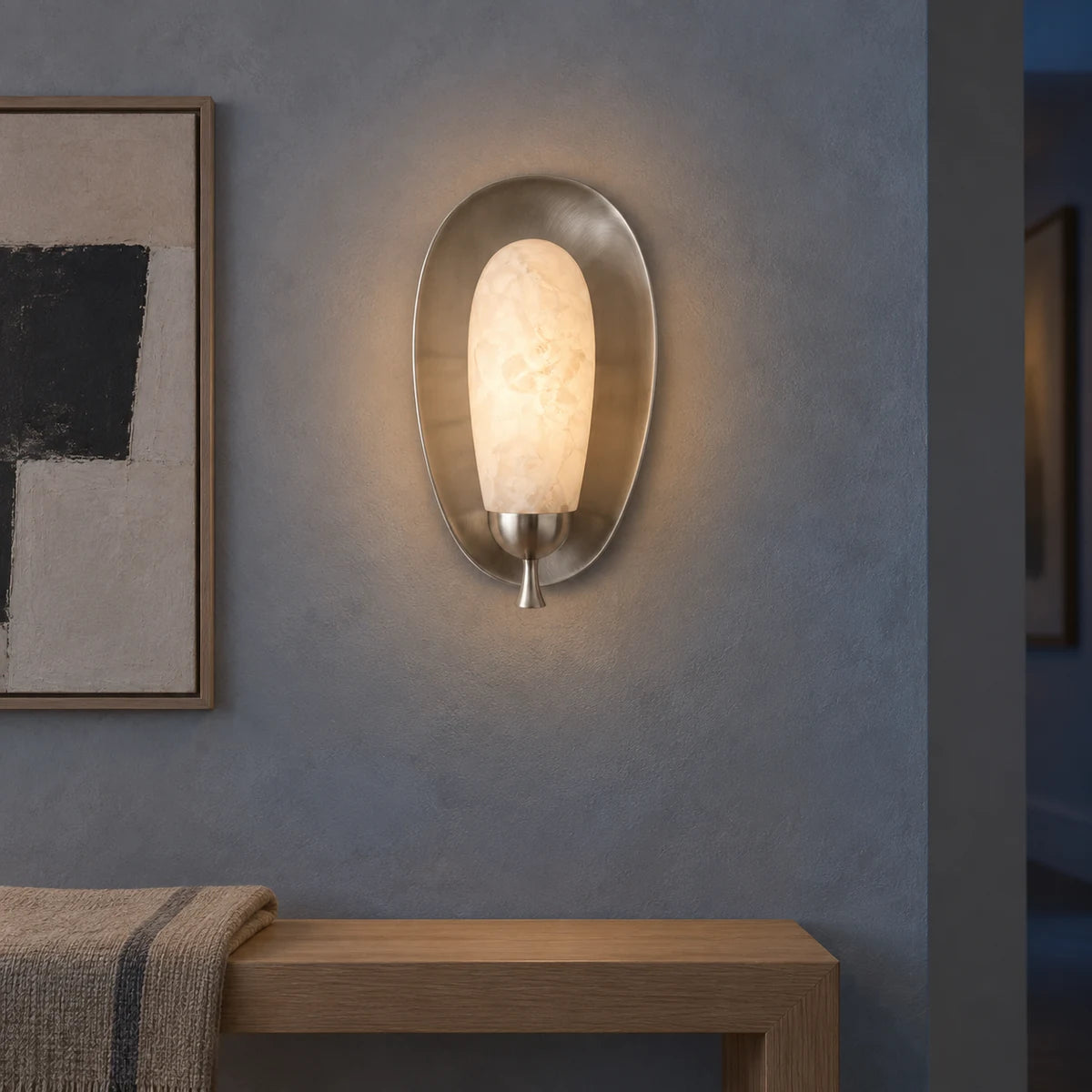 Glowing nickel alabaster wall sconce in blue gray art hallway