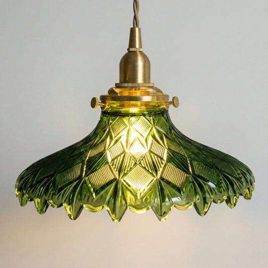 Green glass pendant light with brass fitting on a neutral background