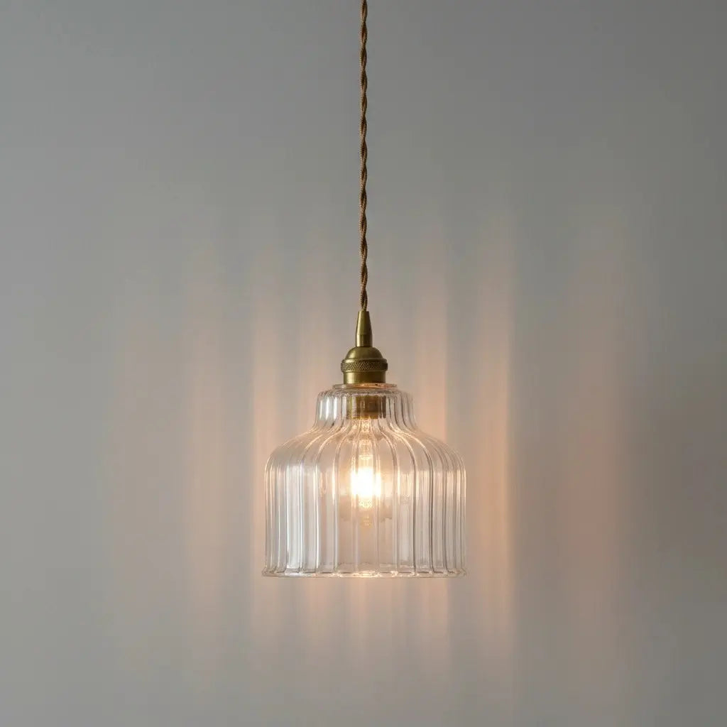 Glass pendant light with brass fixture on a gray background