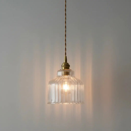 Glass pendant light with brass fixture on a gray background