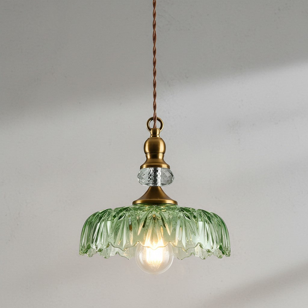 Vintage-style pendant light with green glass shade and brass fixture on a plain background