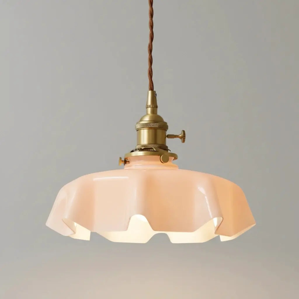 Vintage-style pendant light with pink glass shade and brass fixture on a gray background