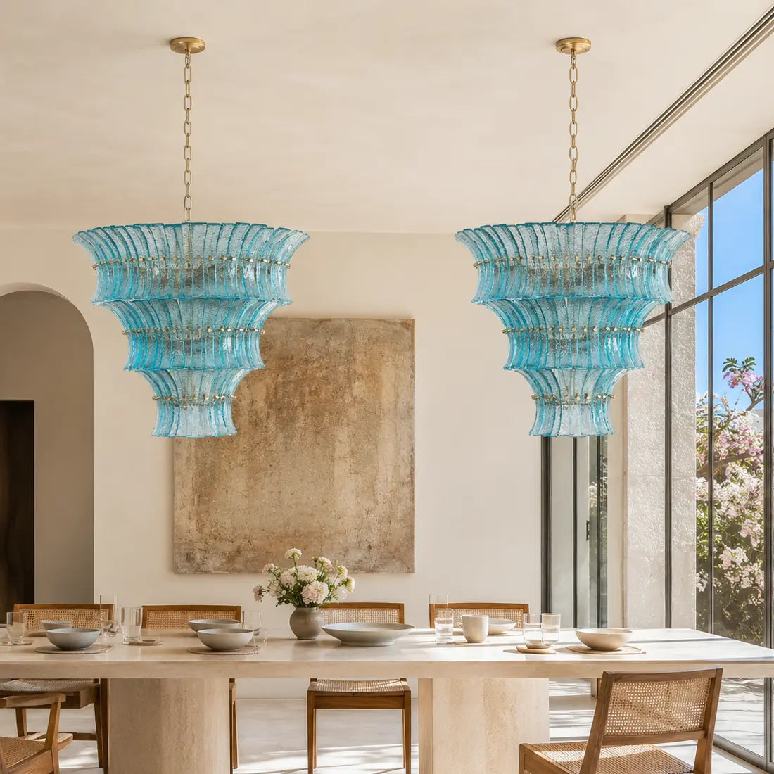 Pair of aqua textured glass tiered chandeliers above a long dining table