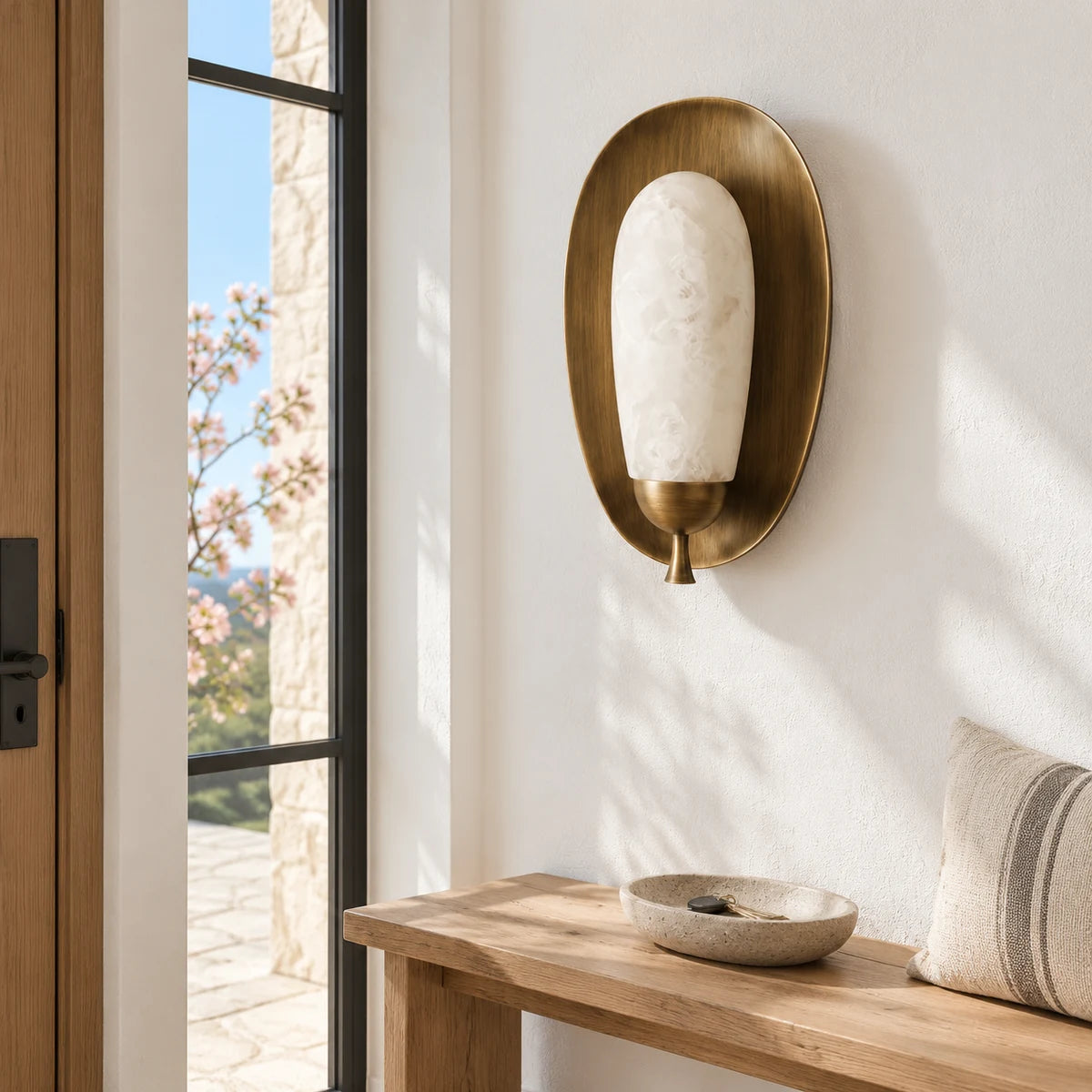 Antique brass alabaster Maelle wall sconce in a bright white entry