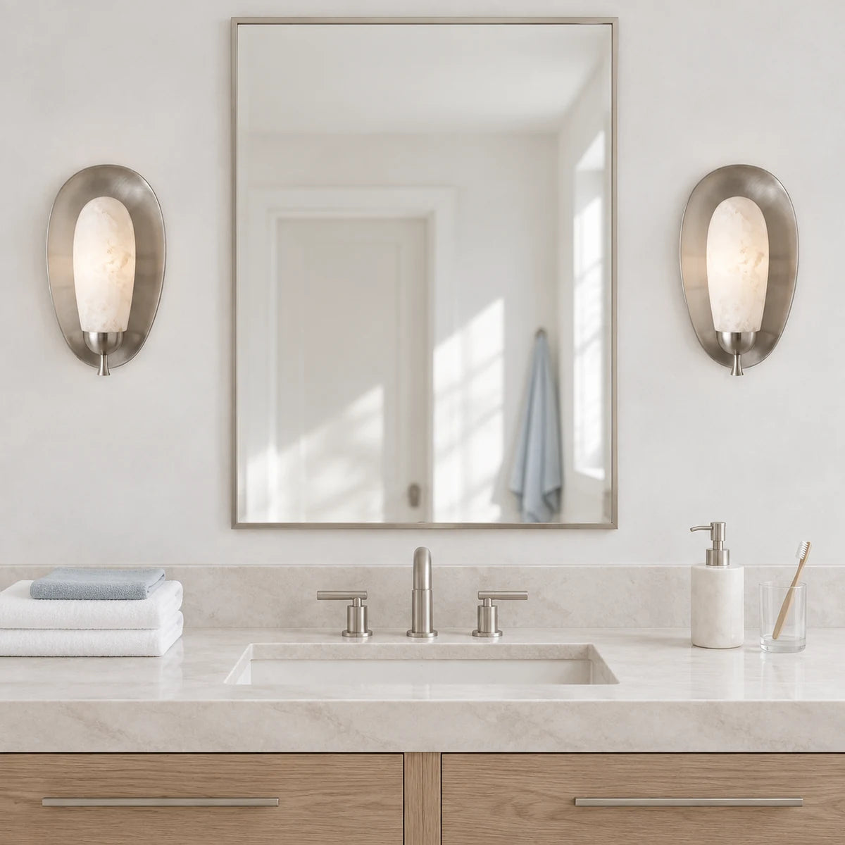 Matching nickel alabaster Maelle sconces beside a white bathroom mirror